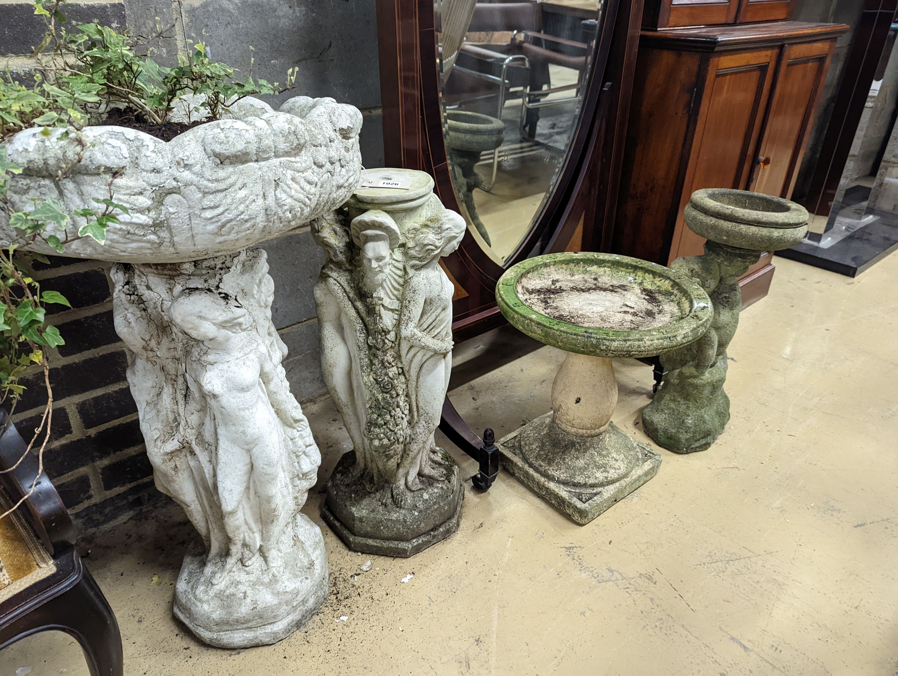 A circular reconstituted stone figural garden planter, diameter 48cm, height 82cm together with two stone bird baths and a plinth
